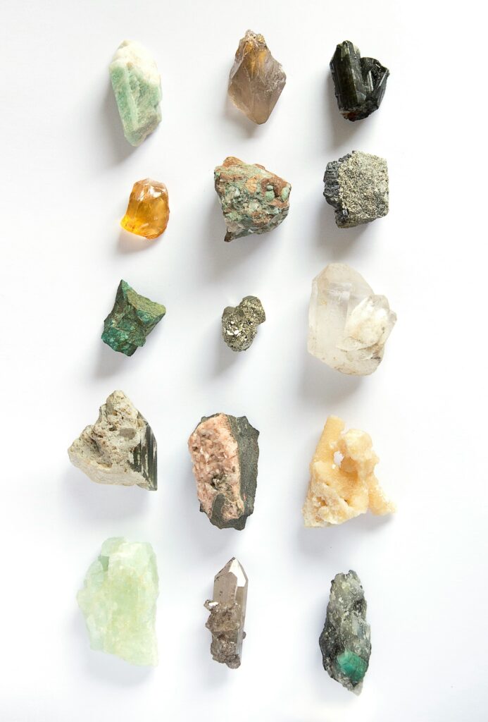All different colors of stones arranged in a 3 x 5 grid up against a white background.